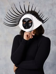 a woman wearing a black and white mask with long eyelashes on her head, covering her face