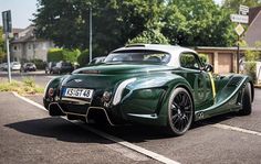 an old green sports car parked in a parking lot