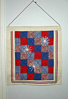 a red, white and blue quilt hanging on a door hanger that has snowflakes on it