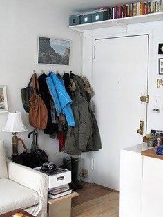 a living room filled with furniture and lots of coats hanging on the wall next to a door