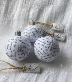 three white ornaments with words on them are tied to twine and placed next to each other