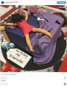 a cake that is on top of a plate with a woman laying on the bed