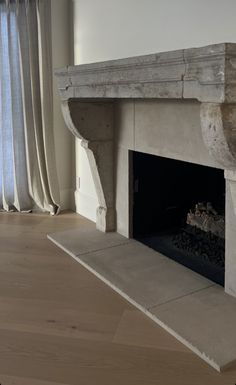 an empty fireplace is shown in the middle of a room with curtains on either side