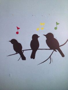 three birds sitting on a branch with musical notes painted on the wall in the background