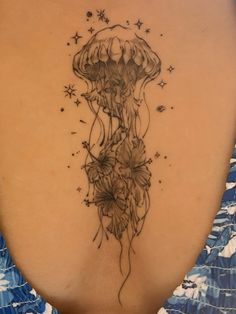 a woman's back with a jellyfish tattoo on her left side ribcage