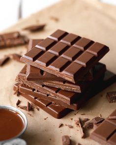 a stack of chocolate bars sitting on top of a table next to a cup of coffee