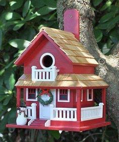 a red bird house hanging from a tree