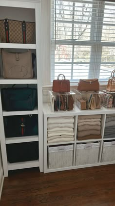 the closet is full of purses and handbags on display in white shelving