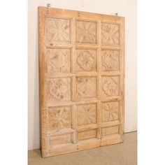 an old wooden door with decorative carvings on the front and side panels, hanging against a white wall