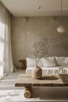 a white couch sitting next to a wooden table in a living room under a window