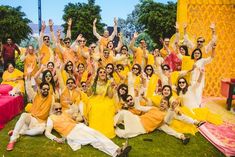 a group of people dressed in yellow and white posing for a photo together on the grass