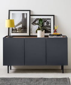 a sideboard with two pictures and a lamp on top