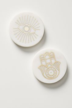 two white and gold buttons with an eye on the front, one in the middle