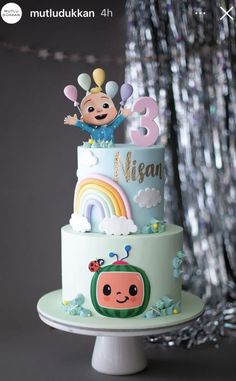 a birthday cake decorated with an image of a cartoon character on the top and rainbows in the background