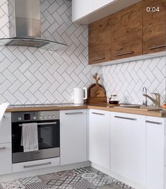 a kitchen with white cabinets and tile flooring on the walls, counter tops, and oven hood