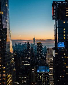 the city skyline is lit up at night, with skyscrapers in the foreground