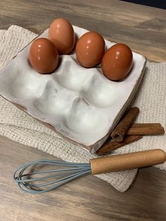 four eggs in an egg carton with cinnamon sticks on a towel next to them