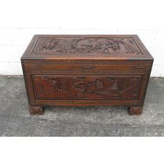 an old wooden box with carvings on the front and sides, sitting on concrete ground