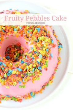 a pink frosted donut with sprinkles on it sitting on a white plate