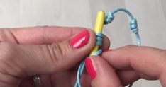 two hands are holding some colorful beads and one has a small yellow bead on it's end