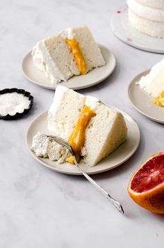 four slices of cake sitting on top of white plates next to grapefruits