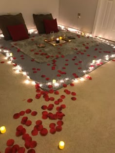 a bed with candles and petals on the floor in front of it that is lit up