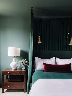 a bedroom with green walls, white bedding and two lamps on the nightstands