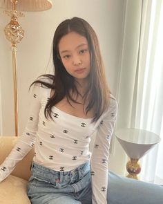 a woman sitting on a couch next to a table with a vase in front of her