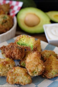 some fried food sitting on top of a white and blue checkered plate next to an avocado