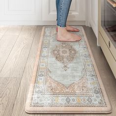 a woman standing on top of a rug in a kitchen