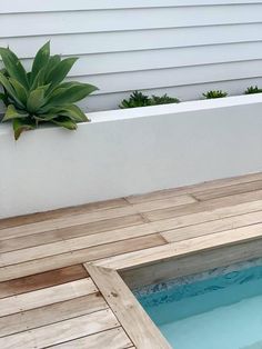 an outdoor hot tub in the middle of a wooden deck with potted plants next to it