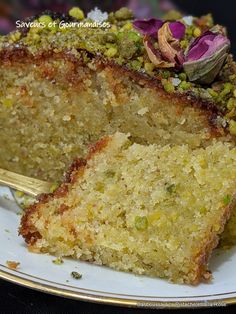 a piece of cake on a white plate with a gold fork in it and some flowers