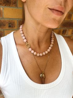 This classic beaded necklace  with toggle clasp is made from genuine Peruvian pink opal (undyed) and gold vermeil findings. It looks great solo or layered with other chains.  MATERIAL Peruvian opal, gold vermeil (18k gold over sterling silver).  SPECIFICATIONS Length: 43 cm (17 inches) Beads measure 10 mm, AAA quality  Handmade in Spain Necklace comes in a gift box Worldwide shipping with registered trackable post Care for gold vermeil jewelry: avoid contact with water and storing in humidity. S Opal Bead Necklace, Single Strand Pink Opal Necklace With Round Beads, Pink Opal Beaded Jewelry, Pink Opal Jewelry With Natural Stones, Gold Vermeil Jewelry, Peruvian Opal, Vermeil Jewelry, Opal Stone, Pink Opal