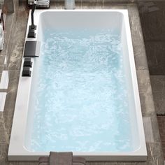 a large white bath tub sitting on top of a tiled floor