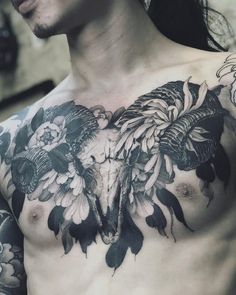 a man with tattoos on his chest has flowers and a cow's skull in the center