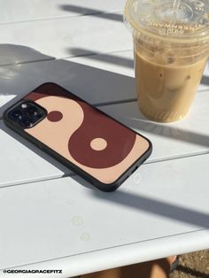 an iphone case sitting on top of a table next to a cup of coffee and a drink