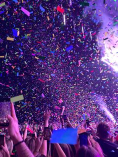 confetti is thrown in the air at a concert with people holding their hands up