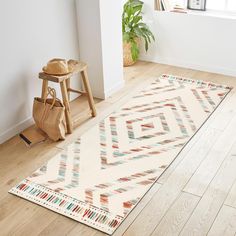 a white rug with multicolored designs on the floor next to a wooden stool