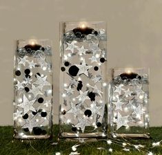 two clear glass vases filled with white and black stars on top of green grass