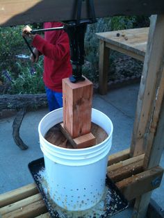 a person is holding an umbrella over a bucket with wood blocks in it on a wooden pallet