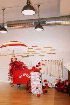 a room with red flowers and umbrellas hanging from the ceiling