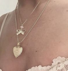 a woman wearing a necklace with a heart and bow on it