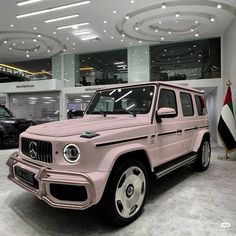 a pink mercedes g - class parked in a showroom