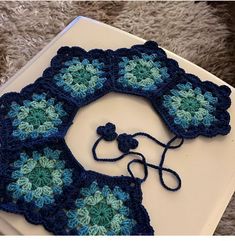 there is a crocheted blue and green doily on top of a book