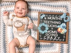 a baby laying on top of a blanket next to a chalk board with writing on it