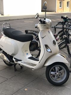 a white scooter parked next to two bicycles