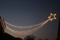 a string of lights hanging from the side of a building in front of a dark sky