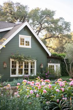 a green house with pink flowers in the front yard