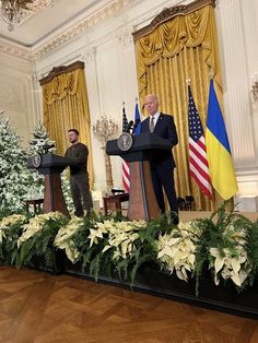 two men standing at podiums in front of flags and other decorations on the floor