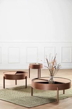 two tables sitting on top of a wooden floor next to a vase filled with flowers